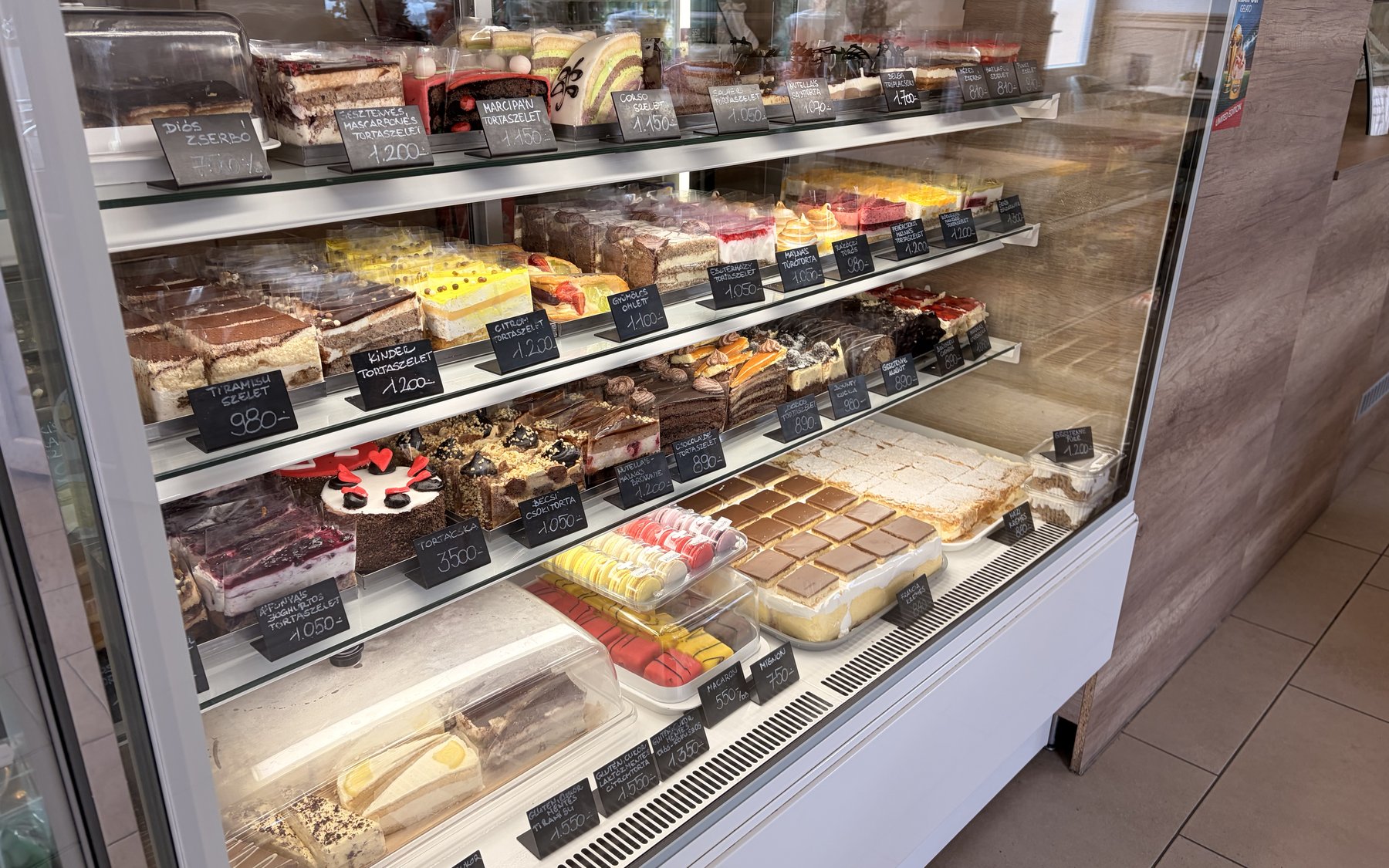 Süteményes vitrin klasszikus szeletekkel: tiramisu, krémes, tortaszeletek