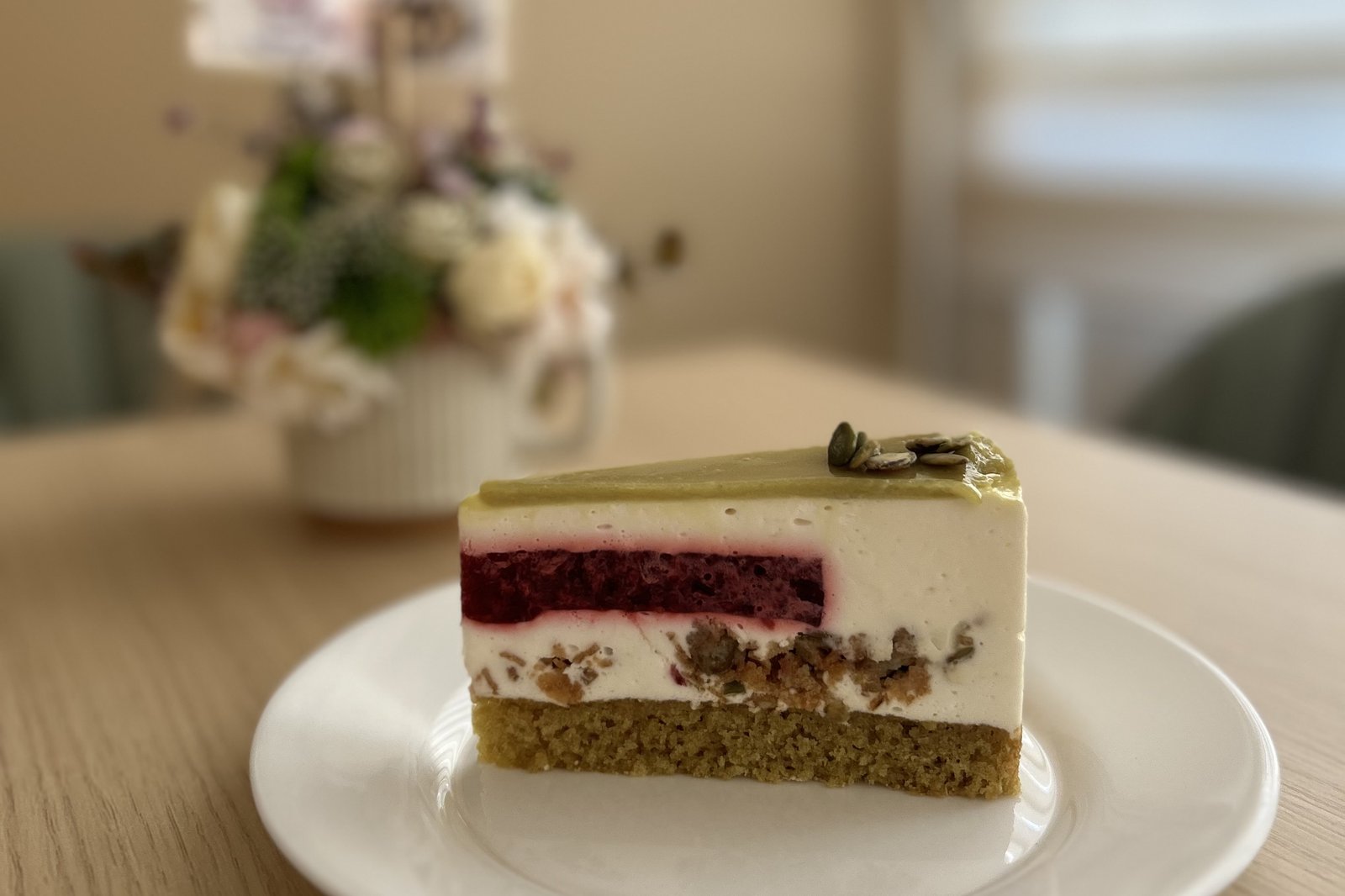 Pisztáciás-málnás tortaszelet fehér tányéron a cukrászdában