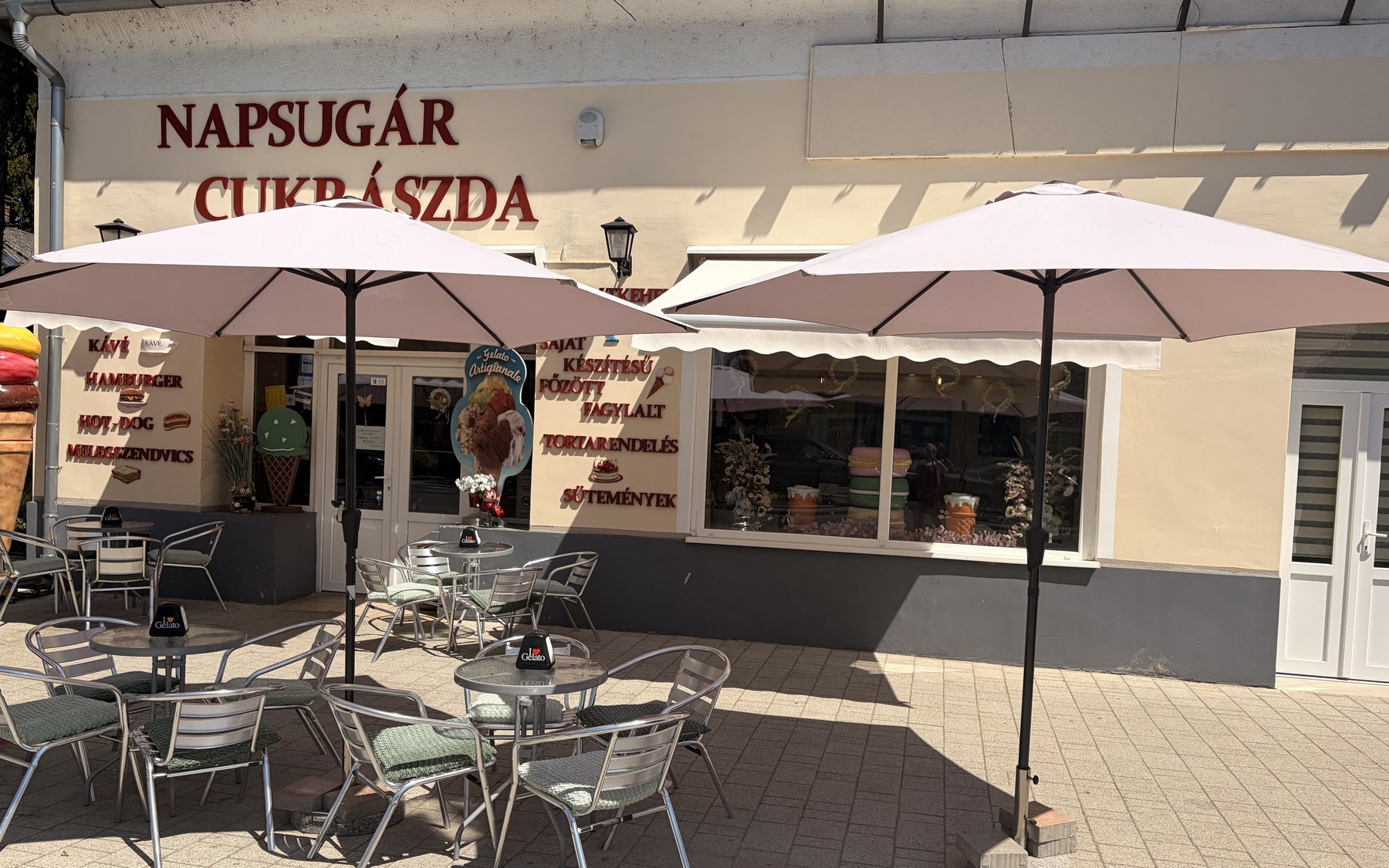 A Napsugár Cukrászda terasza napernyőkkel a bejárat előtt