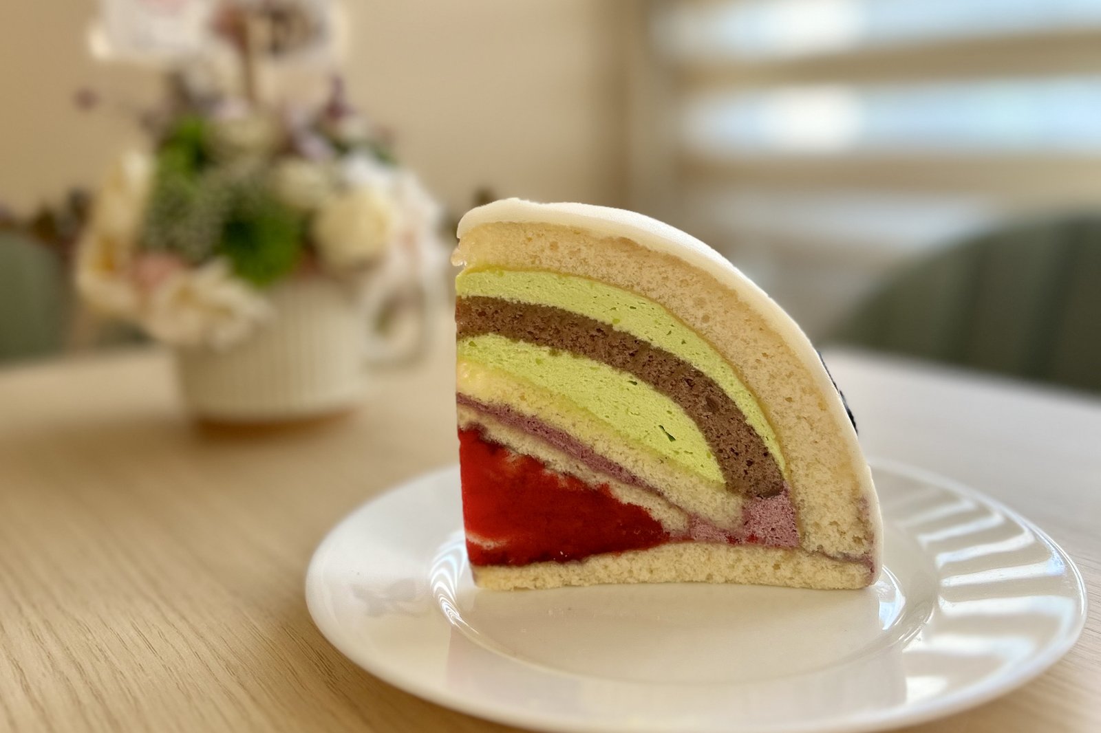 Marcipánburkolatú, színes rétegű tortaszelet fehér tányéron