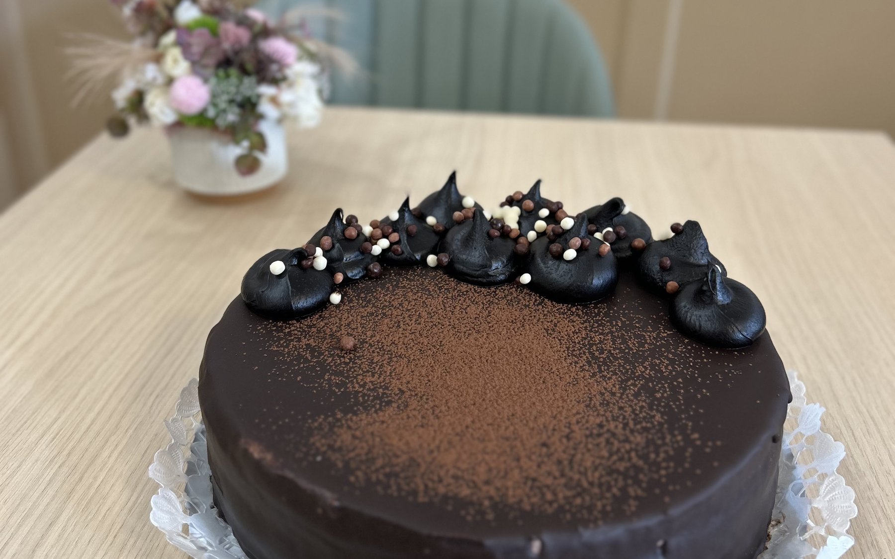 Csokoládébevonatos torta kakaóporral és csokoládédíszítéssel